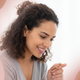 Close-up portrait of a happy young mother gently holding her baby's hand, looking down with a caring expression.